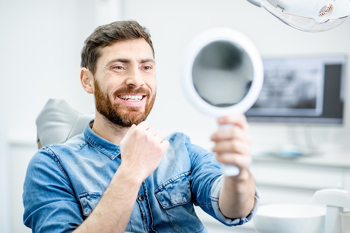 Patient admiring his smile in a hand mirror